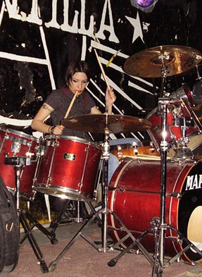 Lara Tarantini playing the drums with her band